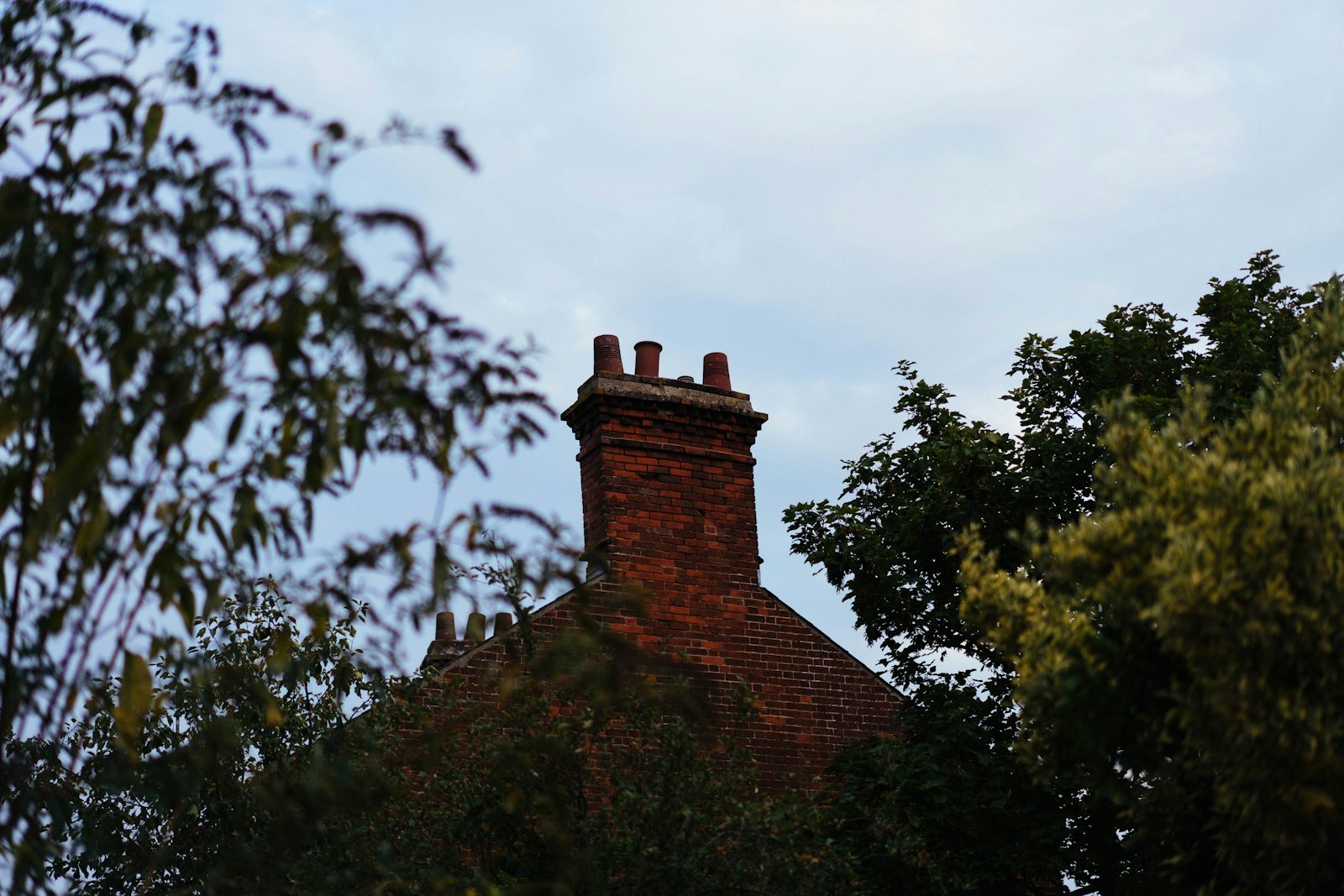 Red brick chimney on a house roof above the trees